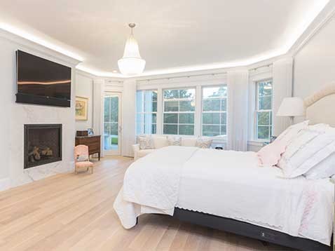 White bedroom with a crystal chandelier and fireplace
